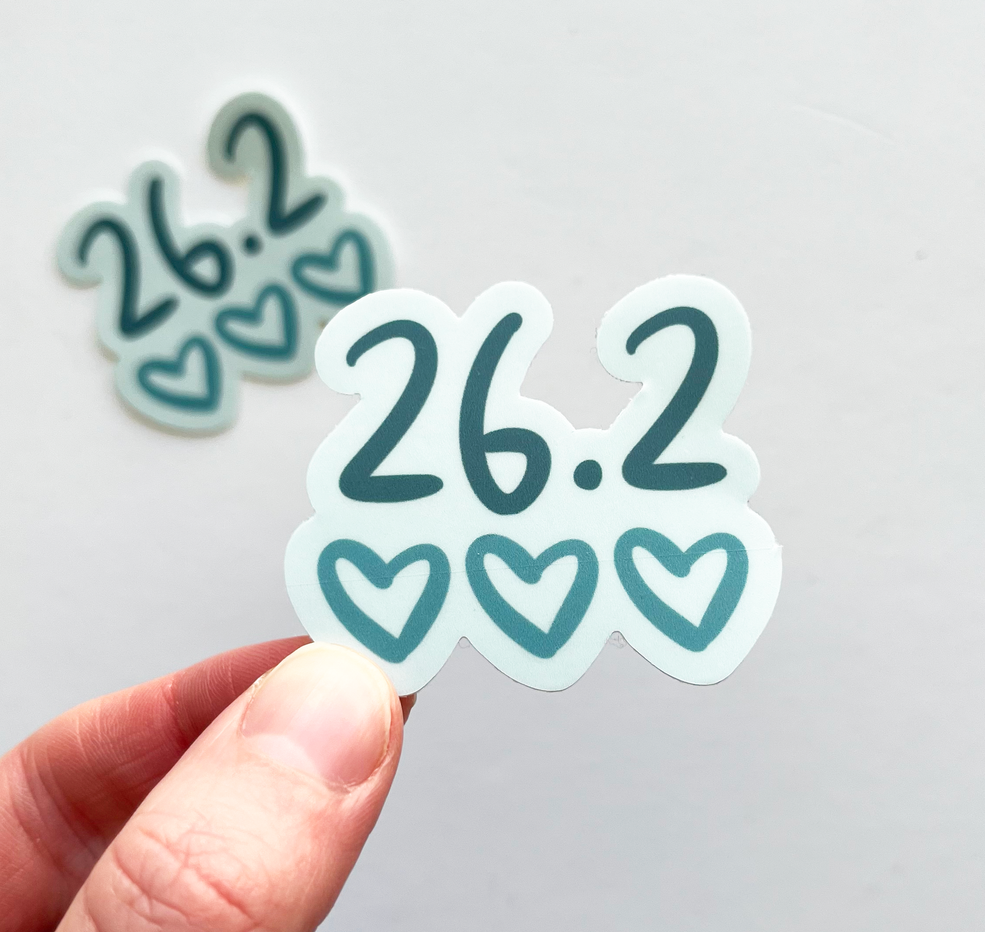 Sticker saying 26.2 with 3 hearts below in blue and teal colors. 