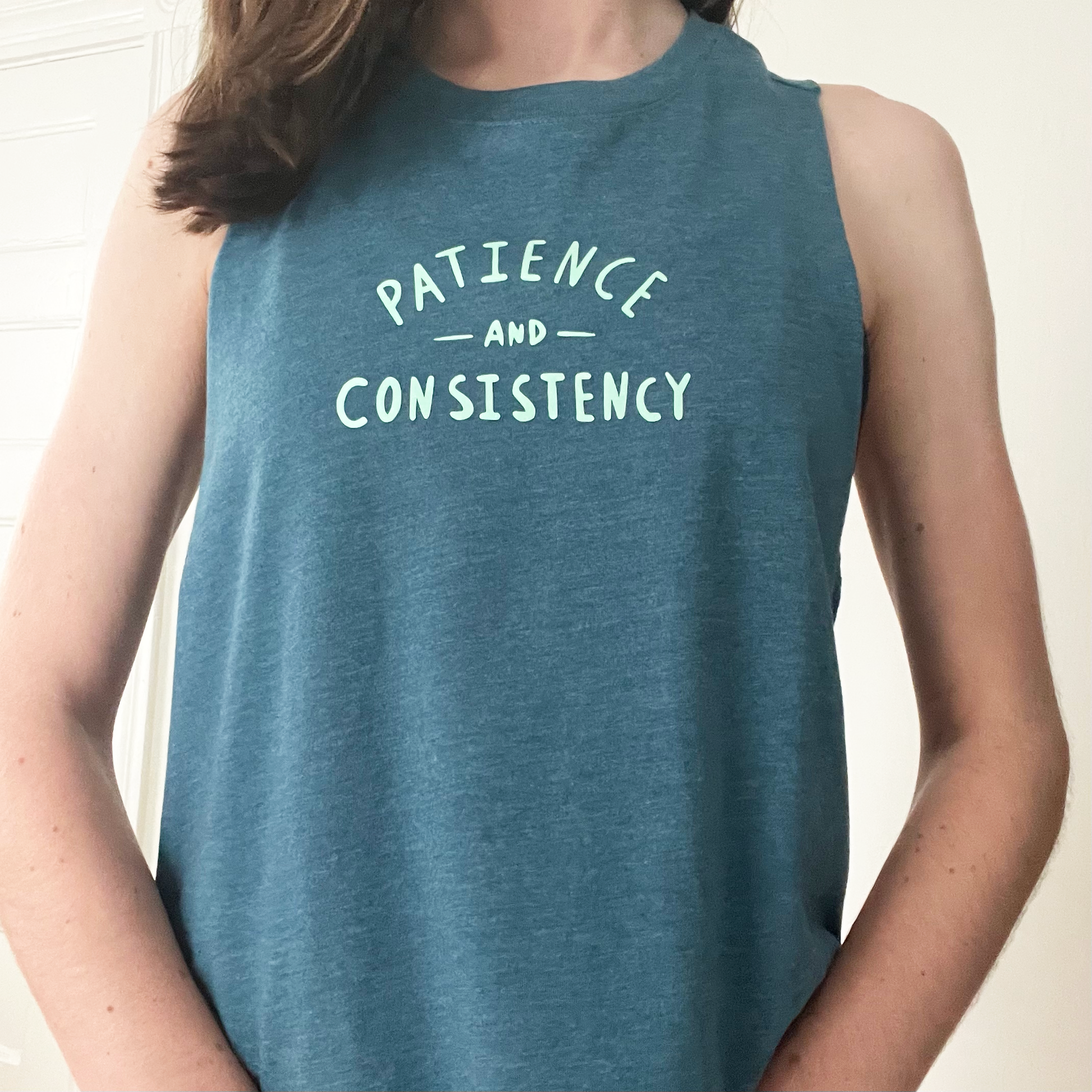 woman wearing blue tank with phrase patience and consistency