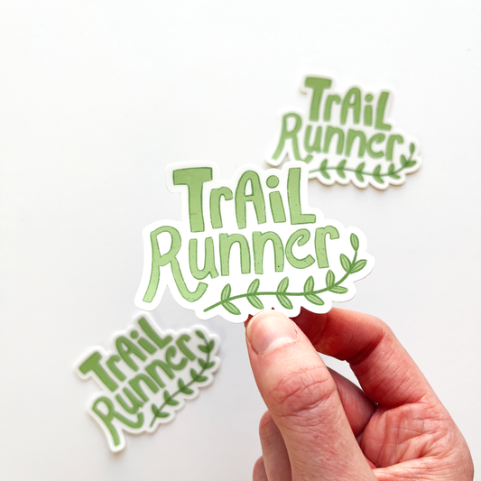 Trail runner sticker in green with a curved leafy vine underneath the word