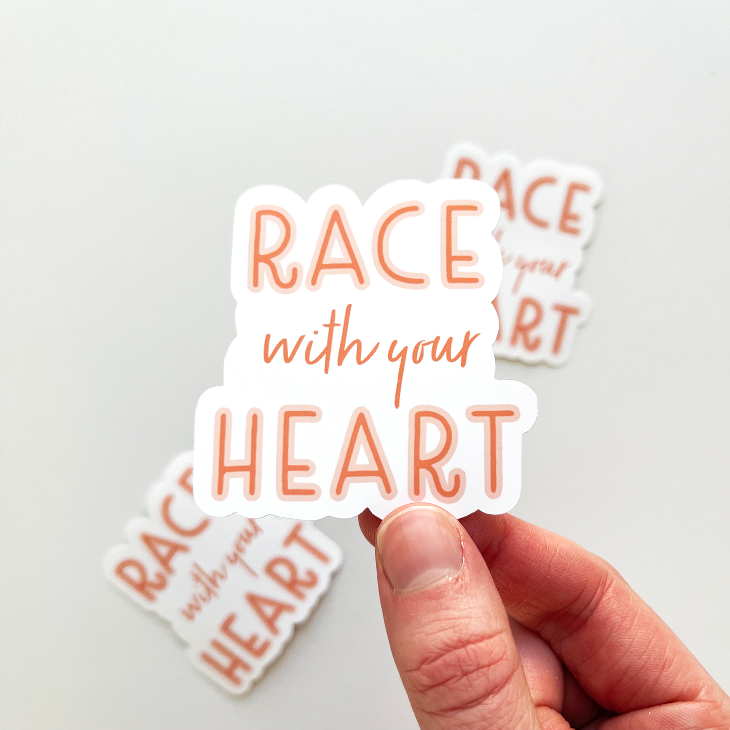 Race with your heart sticker with orange red text outlined in a lighter pink