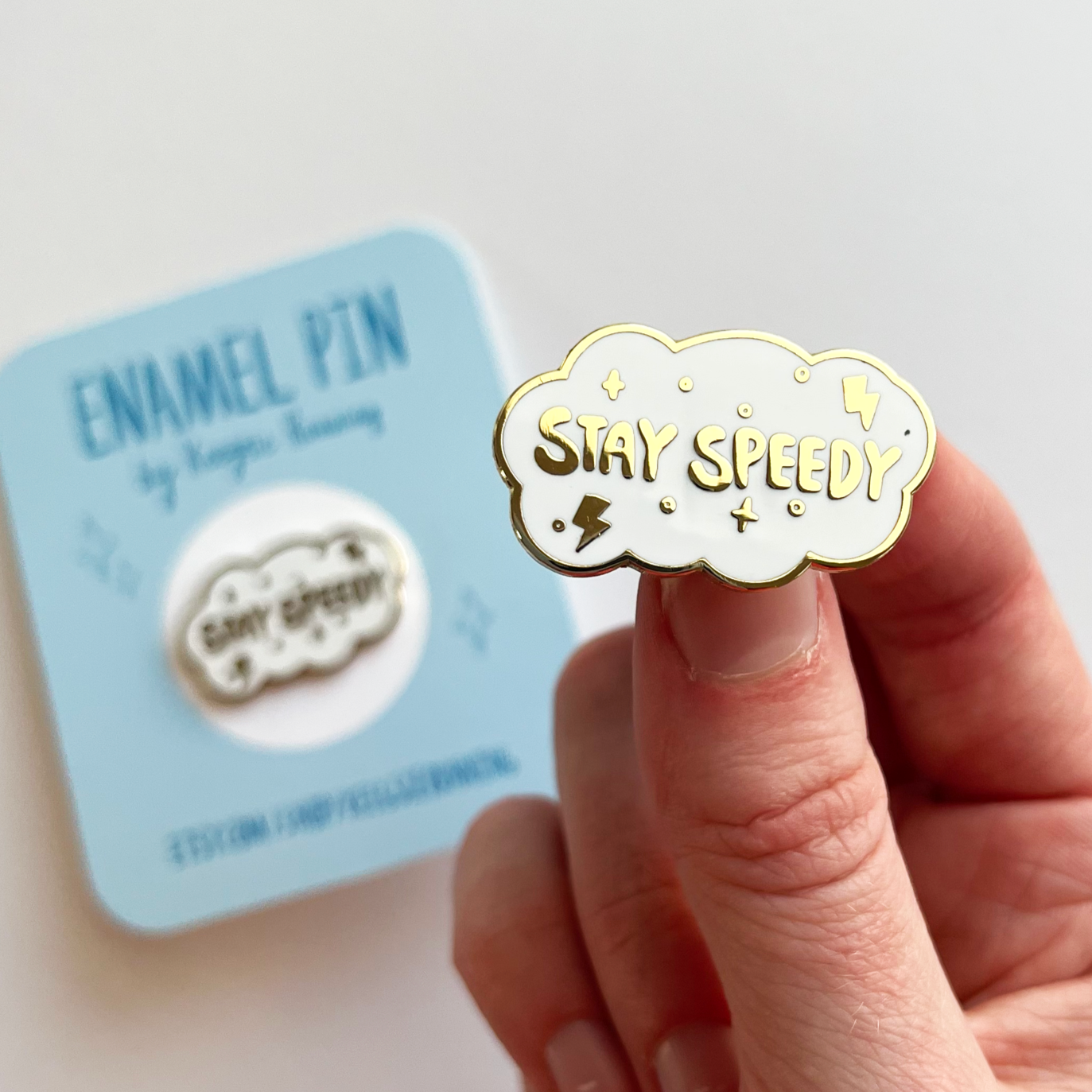 Stay speedy enamel pin. Shaped like a white cloud with gold text.