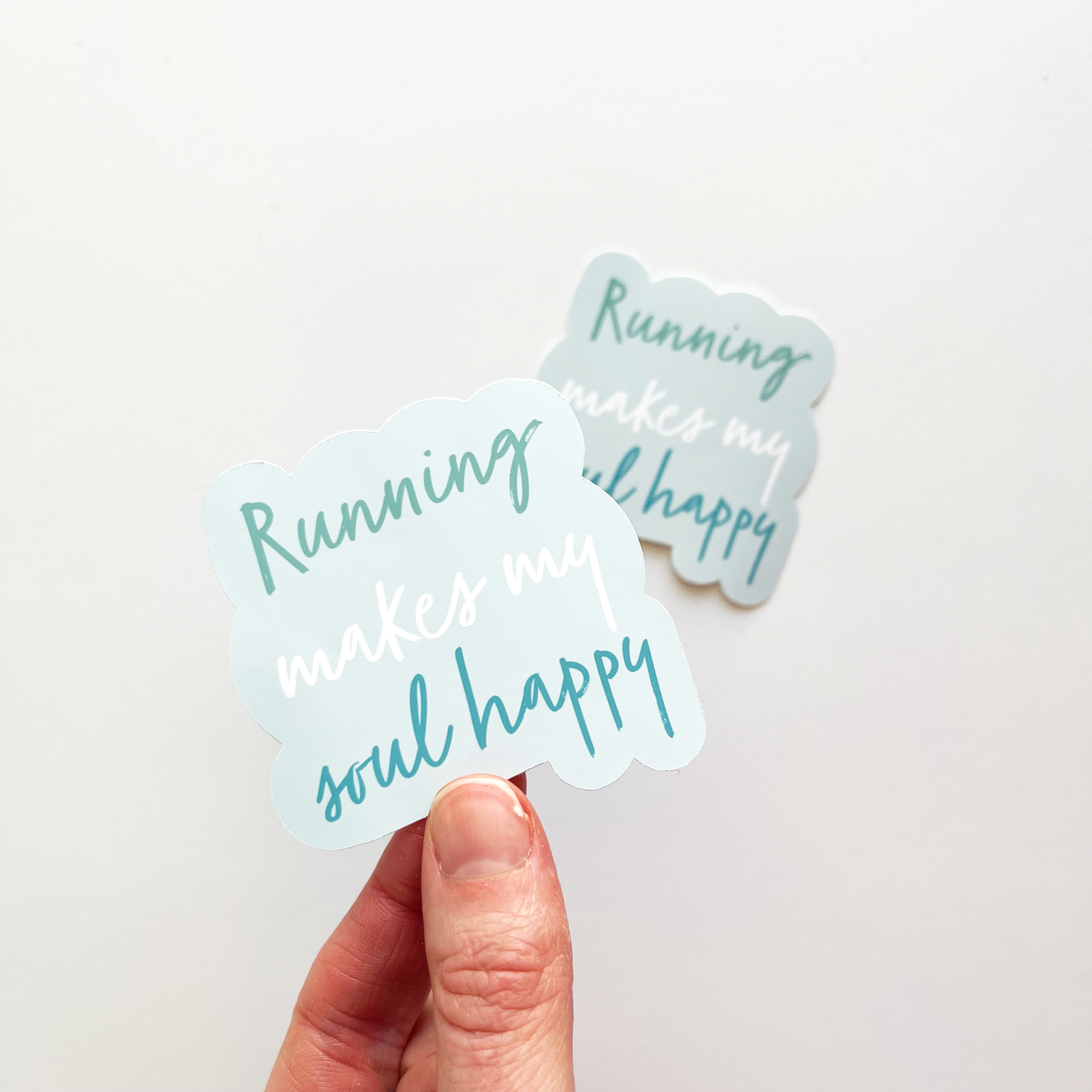 Running makes my soul happy sticker with light blue background. Word running is in teal, the words makes my are in white and the worlds soul happy are in dark blue