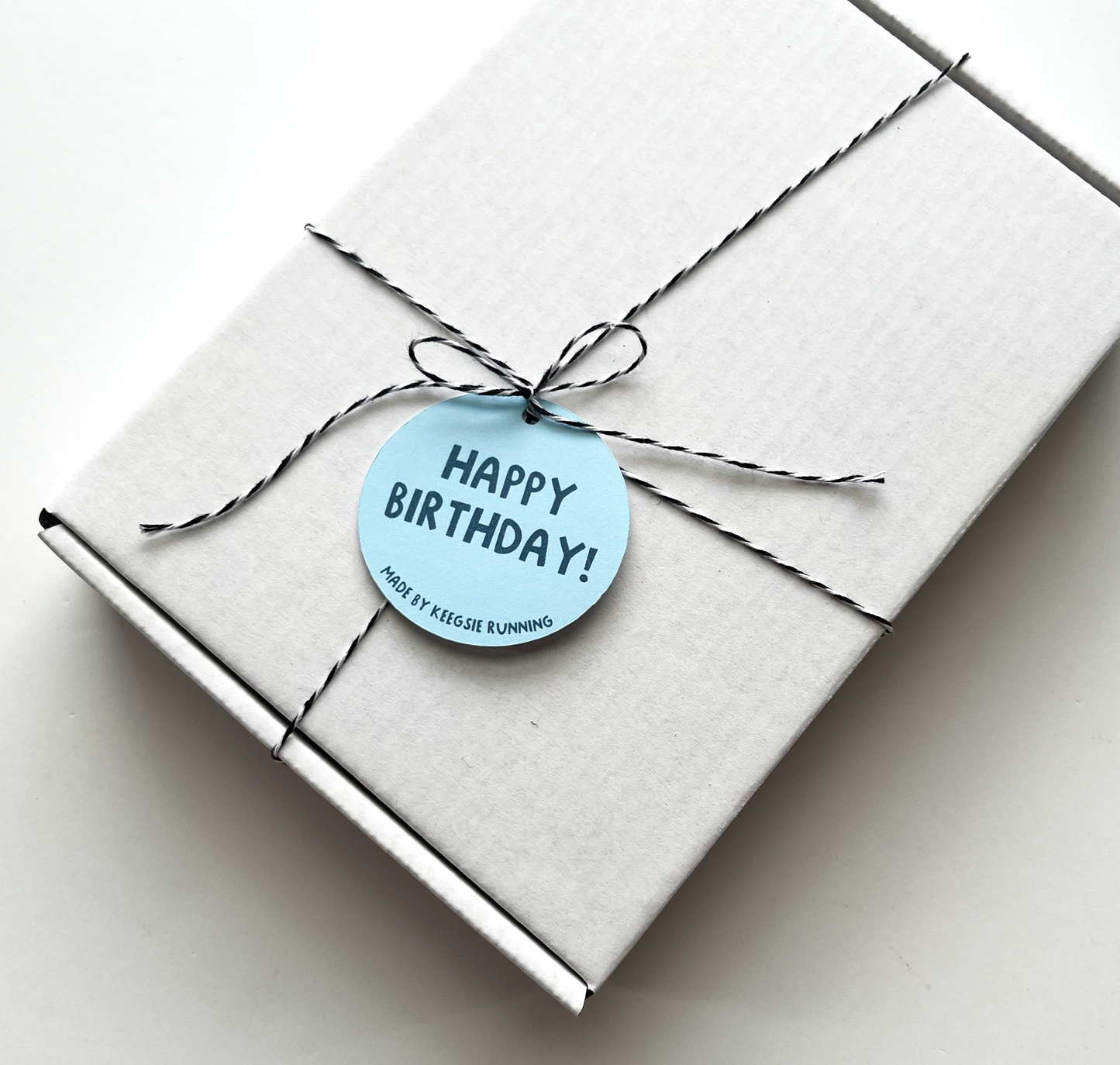 white closed gift box tied with twine and happy birthday tag