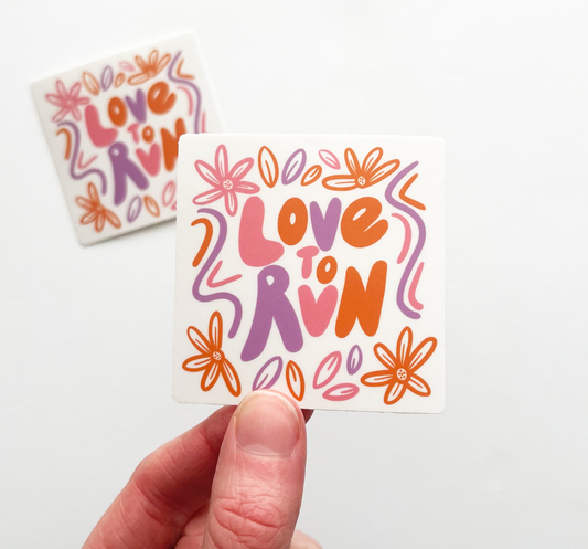 Hand holding love to run square sticker. Love to run is written in bubble letters and surrounded by flowers, leaves and squiggles. Design is alternating color of pink, orange and purple.