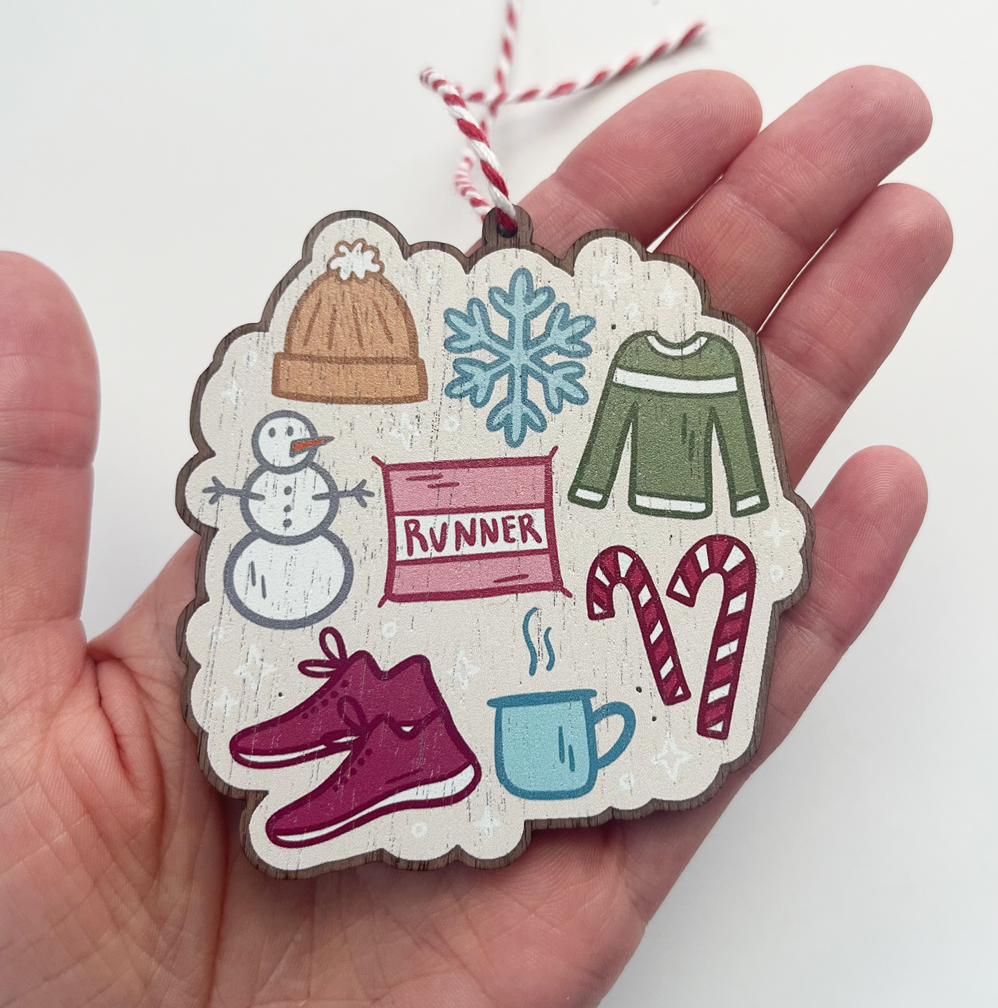 Winter running items like bib, shoes, coffee mug, candy canes, snowman, hat, sweater and snowflake on ornament