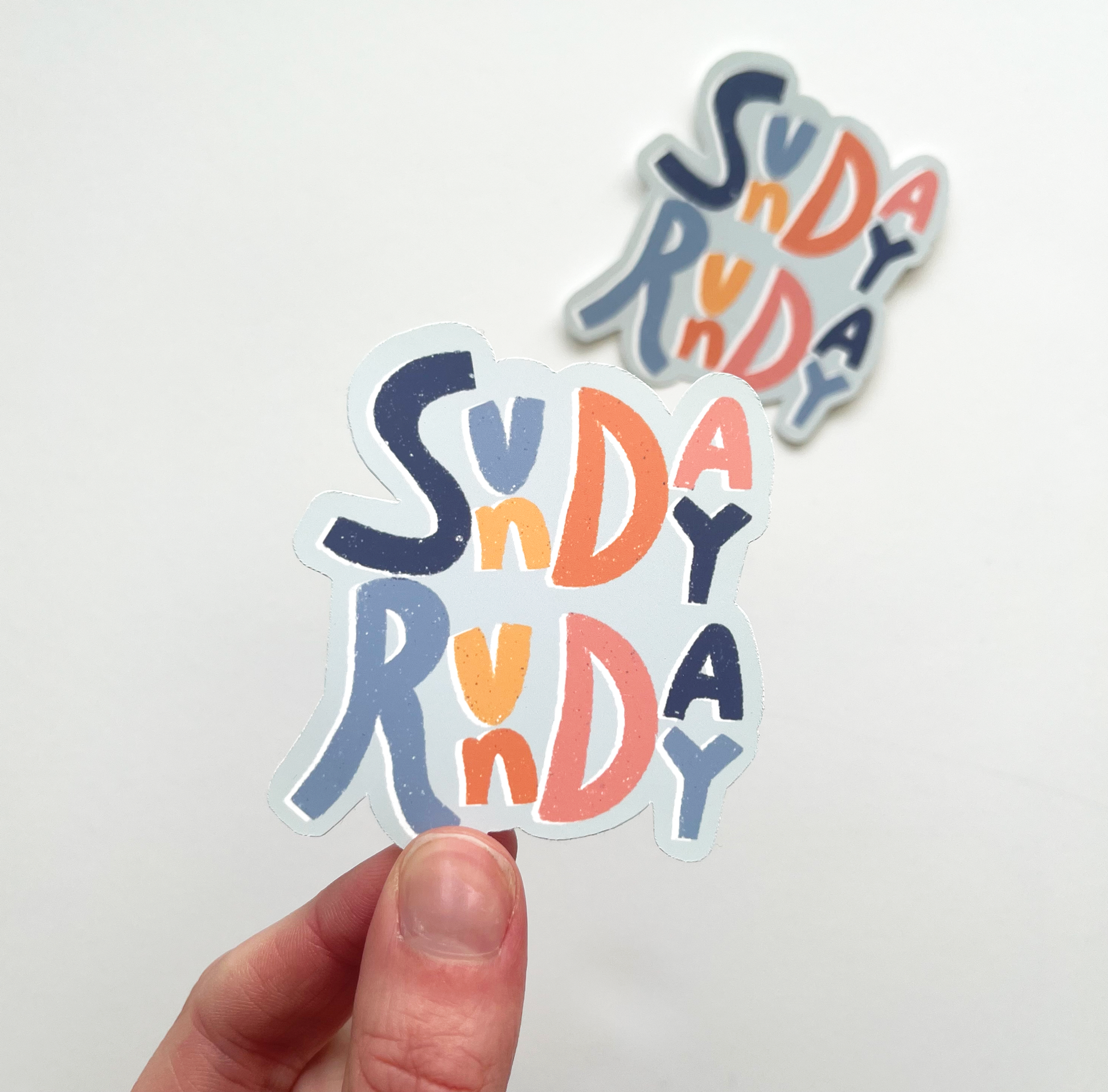 Sunday Runday sticker with alternating letters of dark blue, light blue, yellow, orange and pink