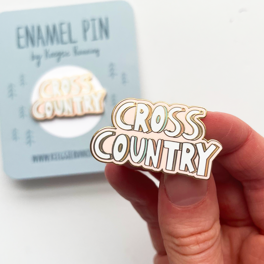 cross country enamel pin being held in hand